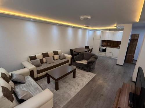 a living room with couches and a table and a kitchen at Fb apartments 2 in Gjilan