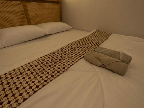 a bed with a white comforter with a tie on it at Happy House BnB Bromo backpacker in Probolinggo