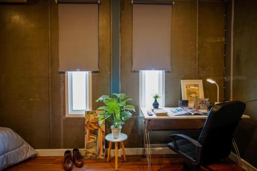 a room with a desk and a chair and two windows at Mama's Tree Homemade Croissant, Bed & Breakfast in Klaeng