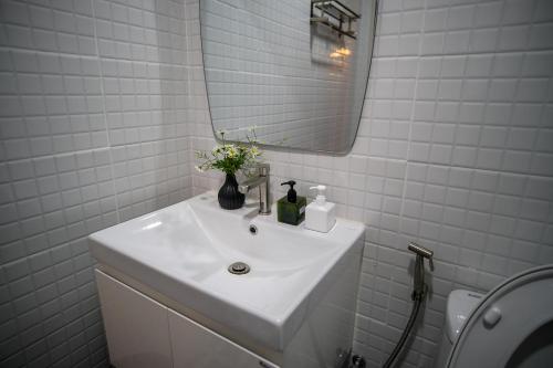 a white bathroom with a sink and a mirror at Mama's Tree Homemade Croissant, Bed & Breakfast in Klaeng