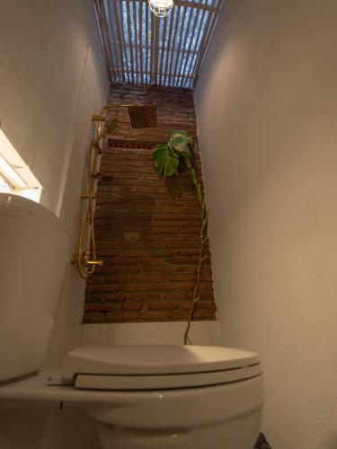 a bathroom with a toilet and a brick wall at Happy House BnB Bromo backpacker in Probolinggo