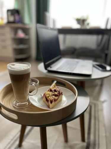 a cup of coffee and a pastry on a table with a laptop at Apartament Piaskowa Mountain & Coffee in Wałbrzych