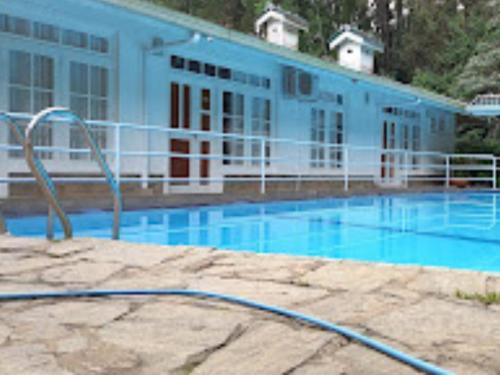 a large swimming pool with a building in the background at Forest Edge Hotel in Ginigathena