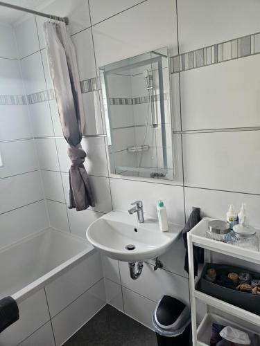 a white bathroom with a sink and a bath tub at Ella's Wolke Appartements - EW6 in Zweibrücken