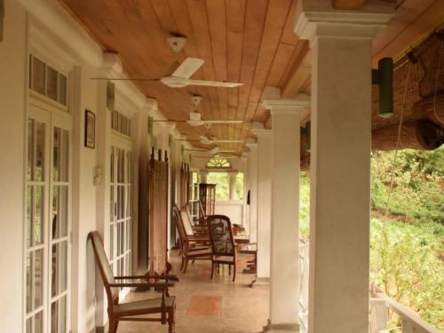 a porch with rocking chairs and a wooden ceiling at Forest Edge Hotel in Ginigathena