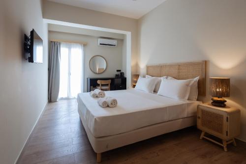 a bedroom with a large white bed with towels on it at Frati Villas Beachfront in Perivolos