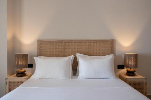 a bed with white pillows and two lamps on tables at Frati Villas Beachfront in Perivolos