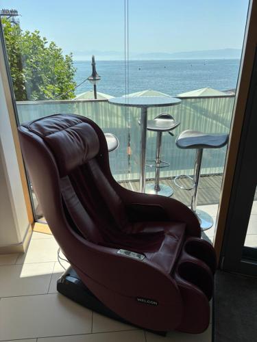 a massage chair on a balcony with a view of the ocean at LakeView Deluxe in Friedrichshafen