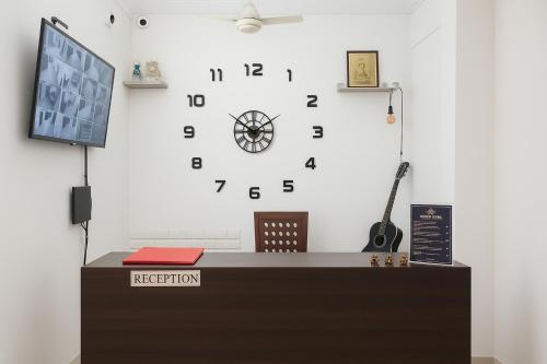 a large clock on a white wall above a desk at Traveler Baga Beach House in Baga