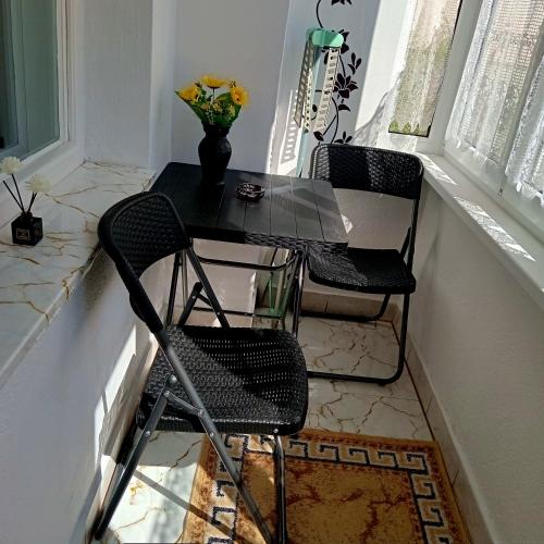 a black table and chairs in a room with a window at Király Apartman in Gheorgheni