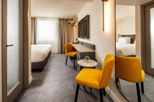a hotel room with two beds and a desk and chairs at Southgate Hotel London in East Barnet