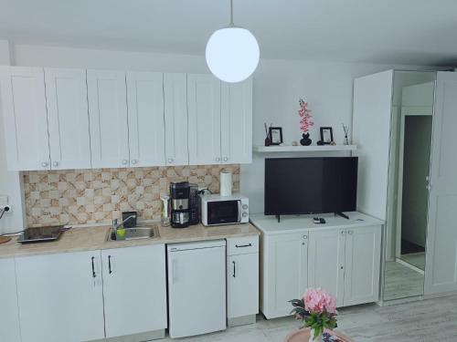 a kitchen with white cabinets and a flat screen tv at Saturn ROOMS in Saturn