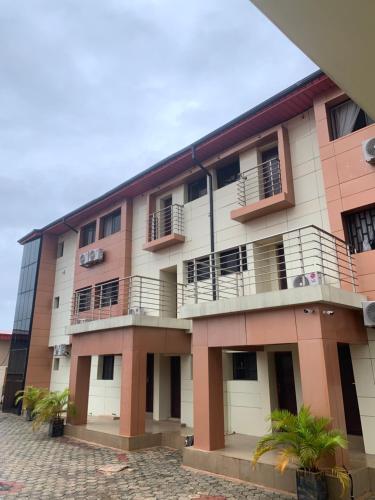 an apartment building with balconies and palm trees at Eagle Nest Apartment and Hotel in Benin City