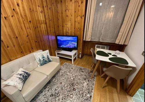 a living room with a couch and a table and a tv at Favoloso alloggio a Branzi in Branzi