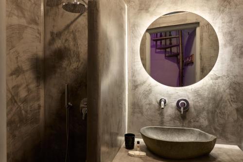 a bathroom with a tub and a round mirror at Canyon Santorini in Fira