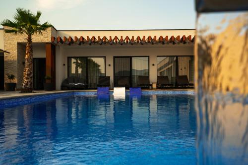 a swimming pool with blue chairs and a house at Villa River in Mostar