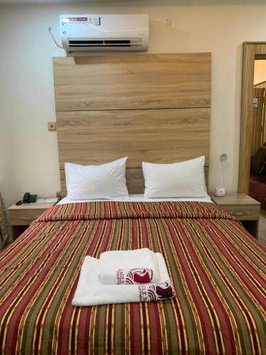 a hotel room with a bed with two towels on it at Eagle Nest Apartment and Hotel in Benin City