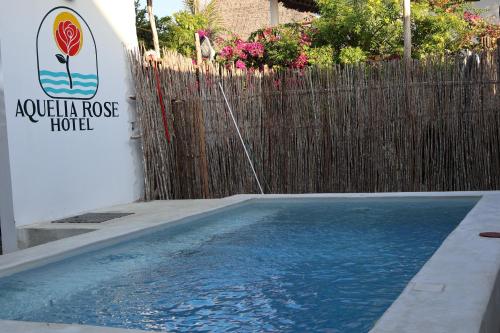 a swimming pool in front of a fence at Aquelia Rose Hotel in Jambiani