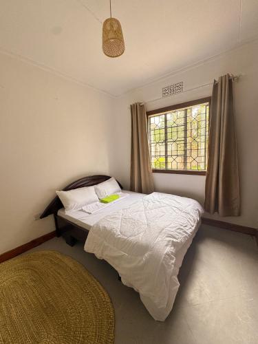 a bedroom with a bed with a window and a rug at Arusha backpackers homes in Arusha