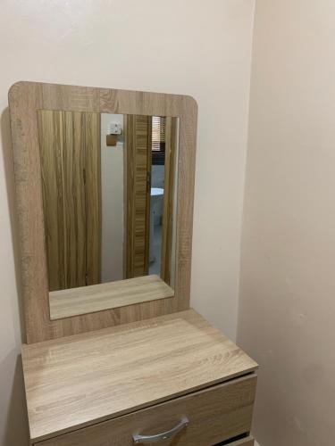 a mirror sitting on top of a wooden dresser at Eagle Nest Apartment and Hotel in Benin City