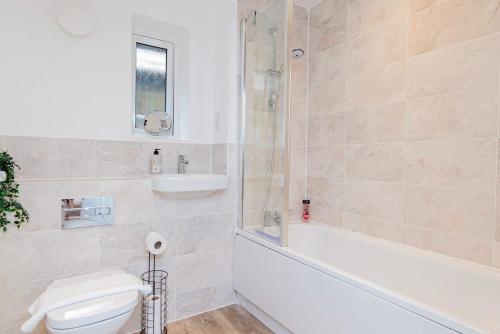 a bathroom with a tub and a toilet and a sink at Stylish 3 Bedroom Home Perfect for Families in Bicester