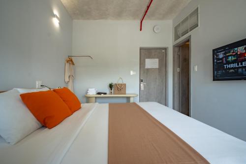 a bedroom with a large white bed with orange pillows at The Up Hotel Phu Quoc Island - The Poolside Escape in Phu Quoc