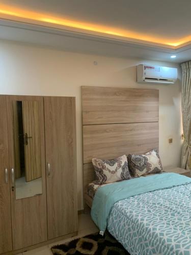 a bedroom with a bed with a wooden headboard at Eagle Nest Apartment and Hotel in Benin City