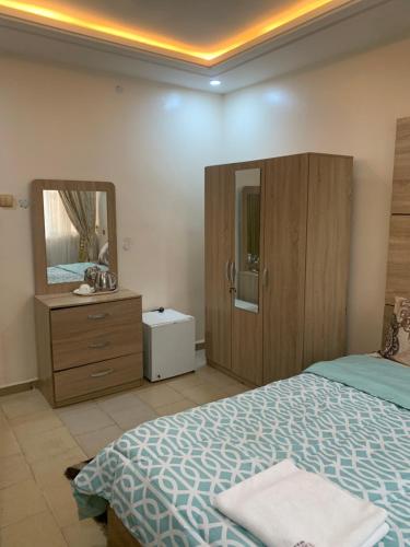 a bedroom with a bed and a dresser and a mirror at Eagle Nest Apartment and Hotel in Benin City