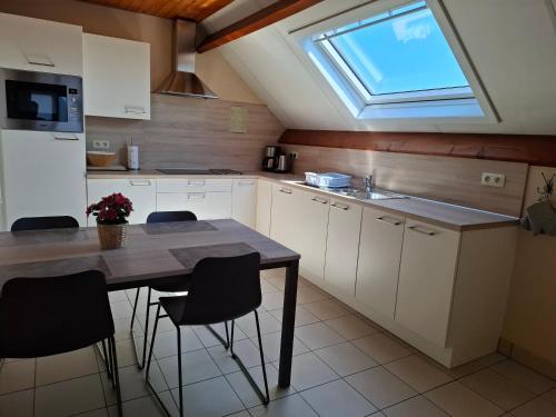 a kitchen with a table with chairs and a window at Huis Pimpernel in Bredene