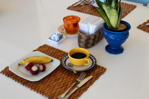 a table with a plate of food and a cup of coffee at Pousada a Capela in Arembepe