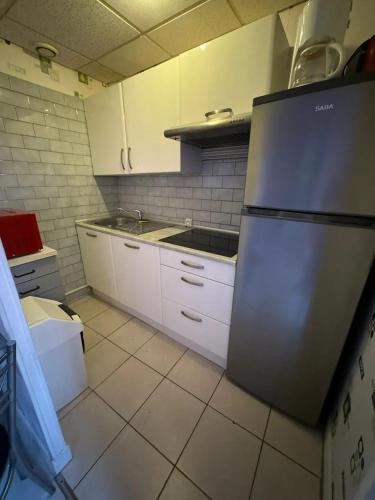 une cuisine avec des armoires blanches et un réfrigérateur en acier inoxydable dans l'établissement Studio charmant à Néris-les-Bains - 25 m² avec terrasse, à Néris-les-Bains