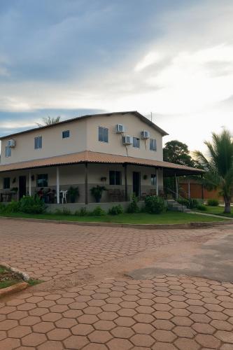 a large white building with a palm tree in front of it at Pousada Alma Jalapoeira - Mateiros in Mateiros