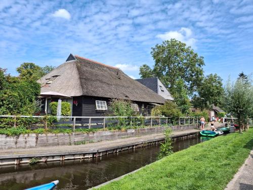a thatch roofed house next to a river at De Galeriet Giethoorn in Giethoorn