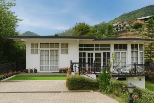 a white house with a balcony and a driveway at The Ceylon Lodge in Nuwara Eliya