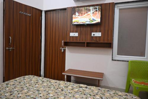 a bedroom with a bed and a tv on the wall at Shree Jee Hotels in Vrindāvan