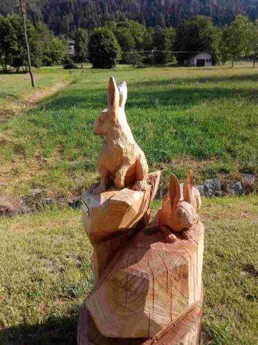 a statue of two rabbits sitting on a tree stump at A Casa mia in Bieno