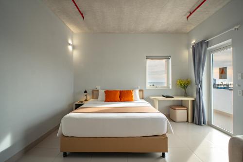 a bedroom with a bed with orange pillows on it at The Up Hotel Phu Quoc Island - The Poolside Escape in Phu Quoc
