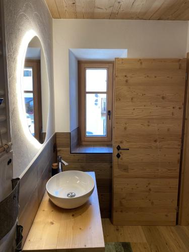 a bathroom with a white sink and a wooden door at My Sweet Home in the Dolomites - appartamento "Ai Vòlti" in Cavalese