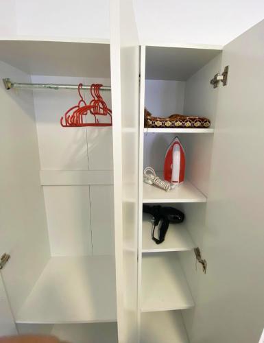 a white walk in closet with white shelves and a red appliance at Studio with Rooftop Pool at Youth City Nilai by D'KAY HOMES, near USIM KLIA in Nilai