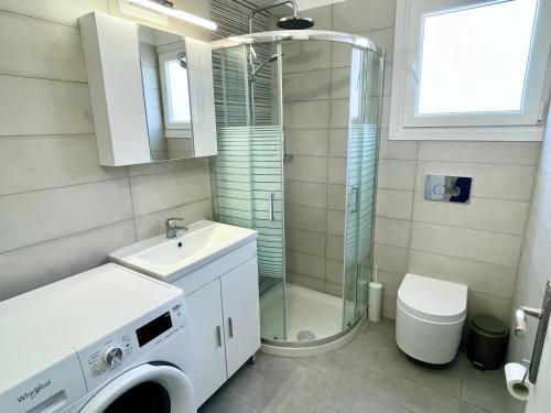 a bathroom with a shower and a washing machine at Berro's Beach House in Litherés