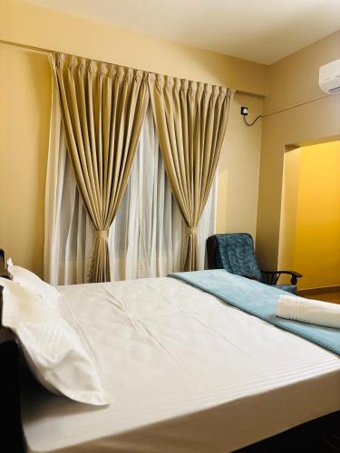 a bedroom with a bed and a chair and a window at Venice villa varkala cliff -luxurious rooms and apartments in Varkala