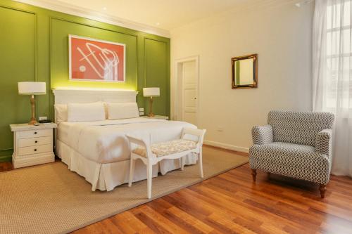 a bedroom with a white bed and a chair at Hotel Boutique Santa Lucia in Cuenca