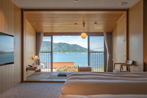 a bedroom with a large window with a view of the ocean at Hotel Kitanoya in Miyazu