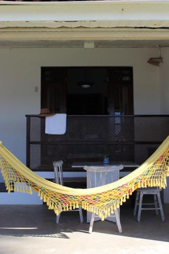 a yellow hammock on a patio with two chairs at Pousada a Capela in Arembepe