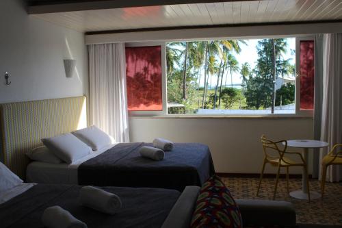 a hotel room with two beds and a window at Pousada a Capela in Arembepe