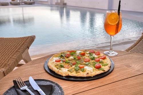a pizza sitting on a table next to a drink at Paolas Sunset in Agios Stefanos