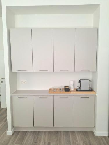 une cuisine blanche avec des armoires blanches et un micro-ondes dans l'établissement Louise Luxe Stay in Central Brussels, à Bruxelles