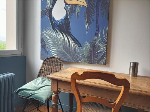 a dining room table with a bird painting on the wall at Maison en ville au calme dans le Finistère in Landerneau