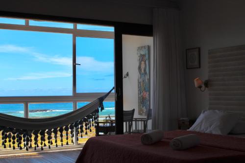 a bedroom with a hammock and a view of the ocean at Pousada a Capela in Arembepe