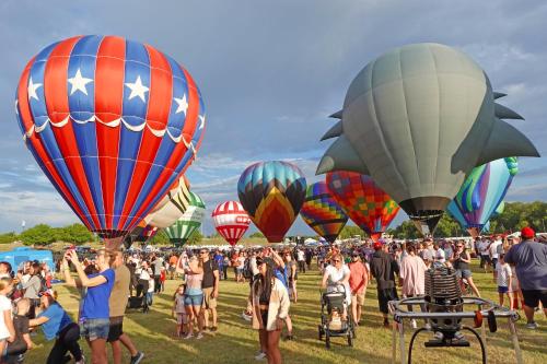 a large group of people standing in a field with hot air balloons at Staybridge Suites Plano - Legacy West Area by IHG in Frisco